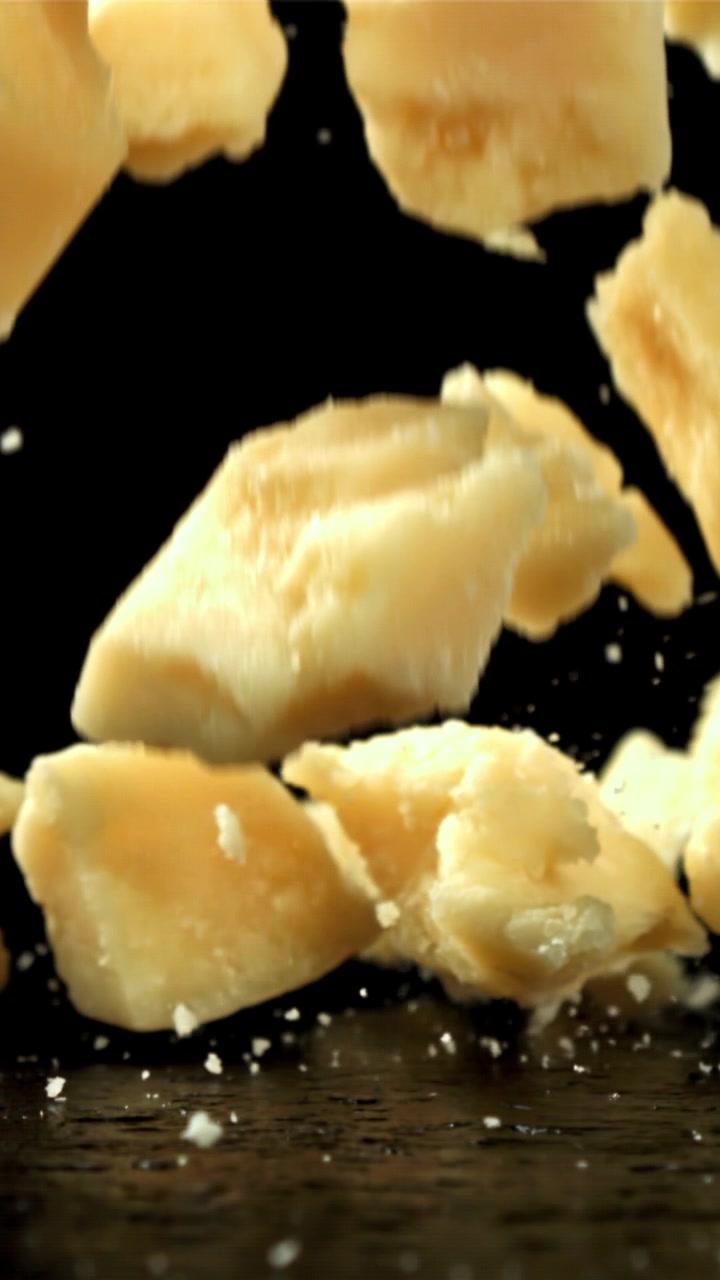 Pezzi di Parmigiano in caduta al rallentatore su sfondo nero