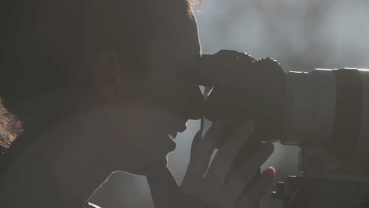 야외에서 긴  ⁇  렌즈로 사진을 찍는 여성의 클로즈업 팬