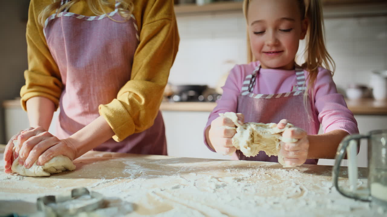 Mom child kneading dough on table closeup. Cute family preparing cookies pastry