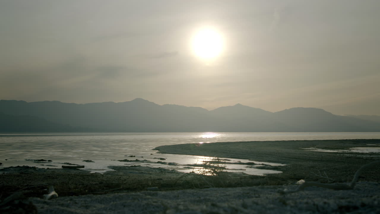 Sunrise over a serene lake with mountains in the background