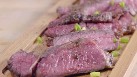 tiro con plataforma rodante en cámara lenta de un bistec medio crudo sazonado en una tabla de madera para servir