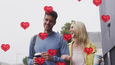 animación de iconos de corazón flotando sobre una feliz pareja caucásica caminando y bebiendo café para llevar