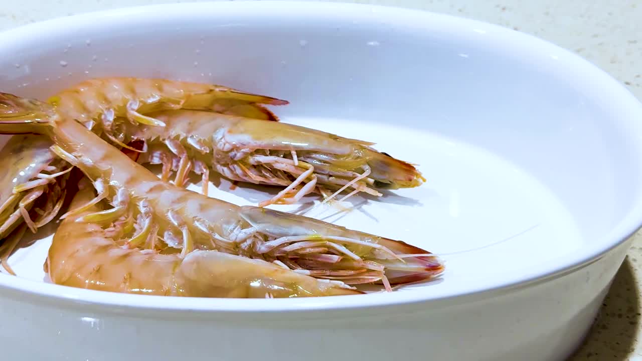 Close-up of fresh prawns neatly arranged in a white bowl, highlighting their texture and color.