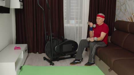 Senior-elderly-man-in-sportswear-doing-weight-lifting-dumbbells-workout-cardio-exercising-at-home