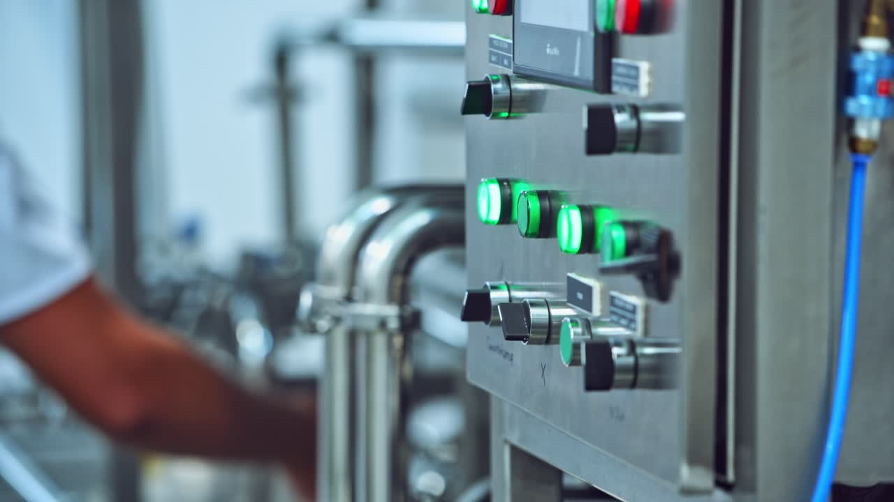 Worker's hand pressing buttons of a mechanical machine at manufacturing plant. Automated equipment in a modernized dairy factory.