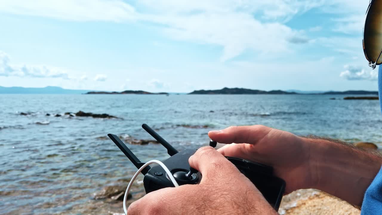 Man with remote control from the drone on the Aegean sea coast. Slow motion