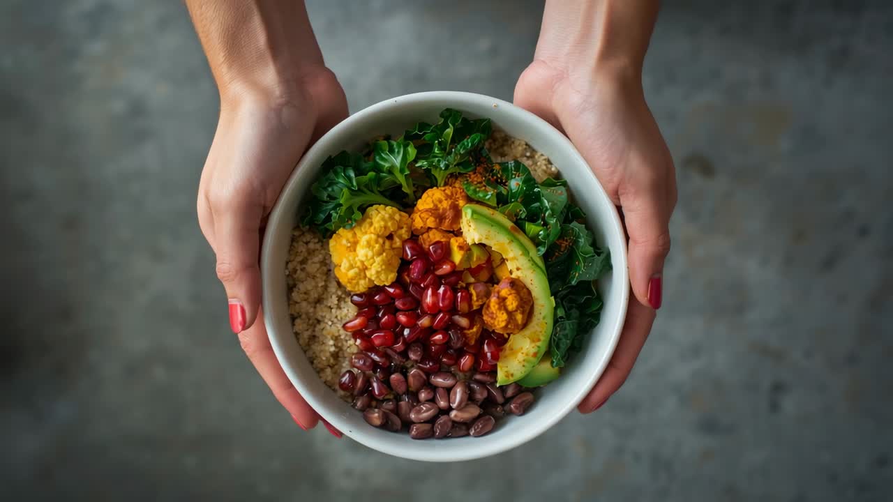 Entering female hands gripping white bowl over countertop, showcasing quinoa pomegranate avocado