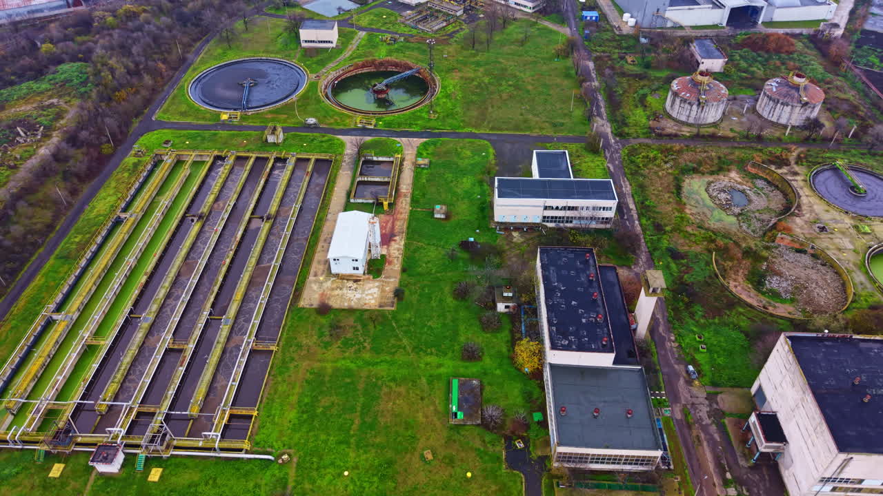 Wastewater treatment facility in urban area showing several ponds and buildings during daylight