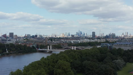 Sliding-reveal-of-Thames-river-and-Chelsea-Bridge.-Aerial-view-with-cityscape-in-background.-London,-UK