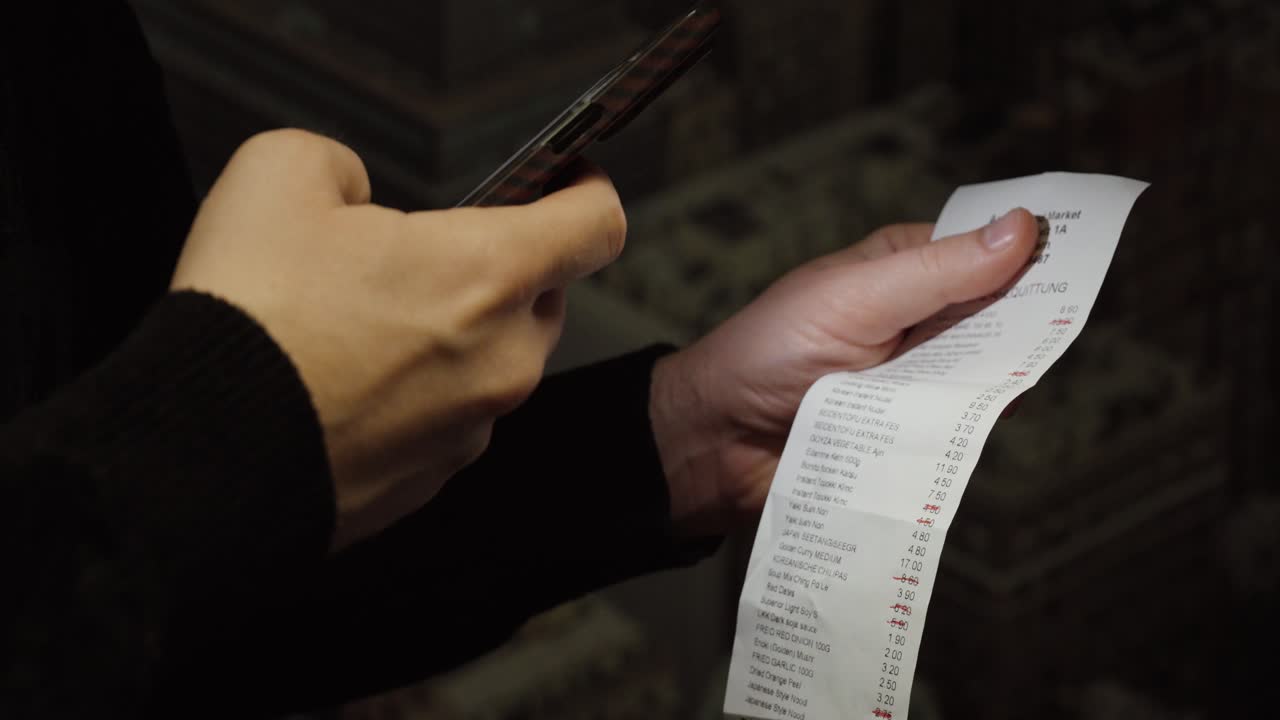 Close-up of a person holding a receipt and using a smartphone to scan and document expenses for digital reimbursement and record keeping