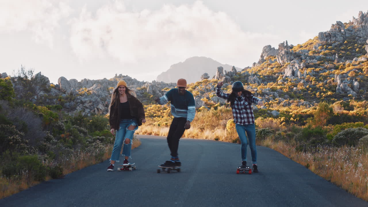 felices amigos multiétnicos longboarding juntos montando patineta crucero en la carretera del campo divirtiéndose pasar el rato disfrutando de unas vacaciones de verano relajadas