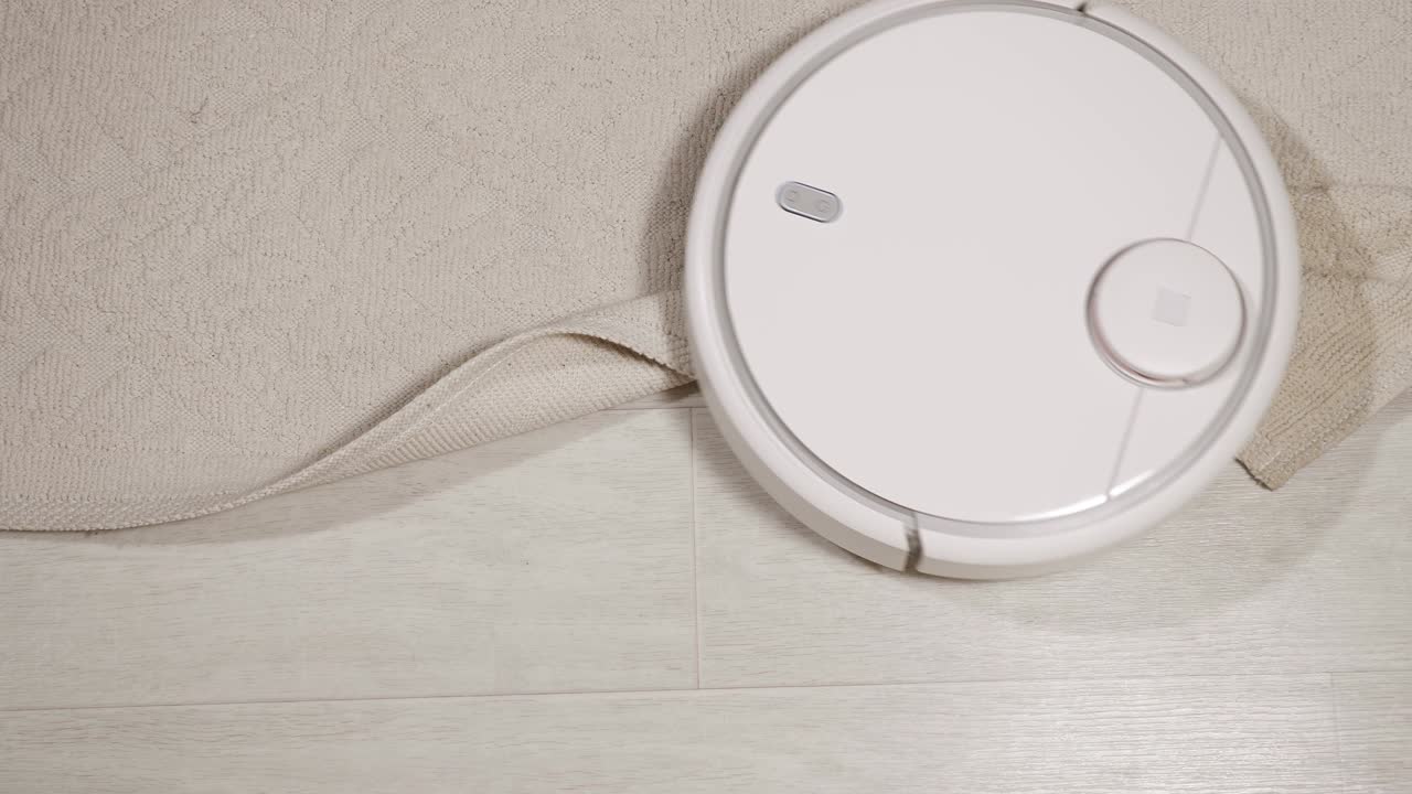 White robot vacuum cleaner cleans carpet top view