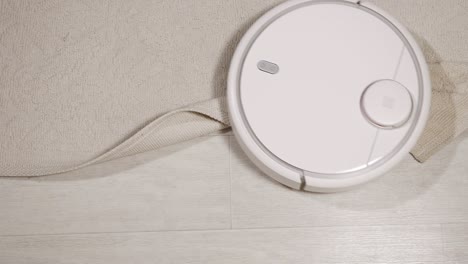 white robot vacuum cleaner cleans carpet top view