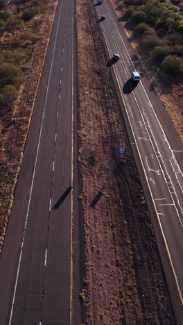 vista aérea vertical del tráfico en la ruta del estado de arizona al atardecer, paisaje, coches y asfalto agrietado, revelando una toma de drone