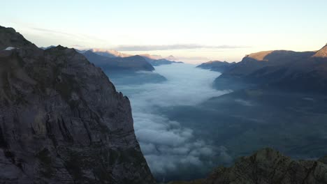 drone shotflying backwards and upwards at gleckstein hut in the alps of switzerland during a colorful and clear sunrise in the summer