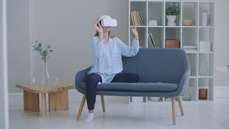 woman using glasses virtual reality simulator playing video games in living room female feeling happy using relax time lying on sofa at home. lifestyle women relax at home concept.