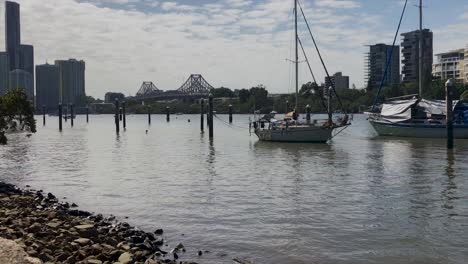 barco en el río brisbane con story bridge y edificios en segundo plano.