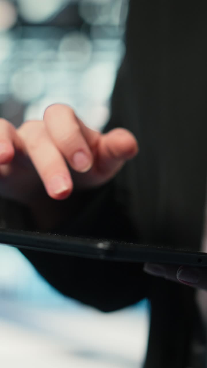Video verticale. Primo piano di un analista di cybersicurezza di data center che usa un tablet per condurre un audit.