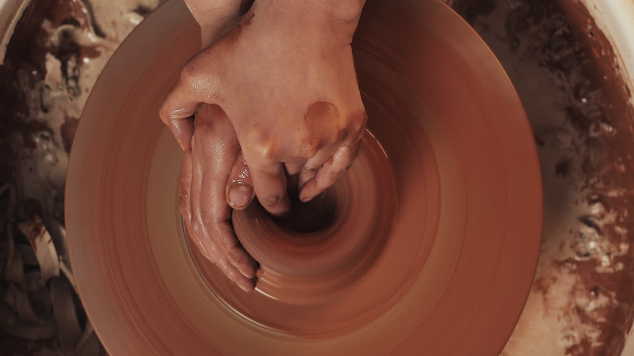 manos moldeando arcilla en una rueda de cerámica