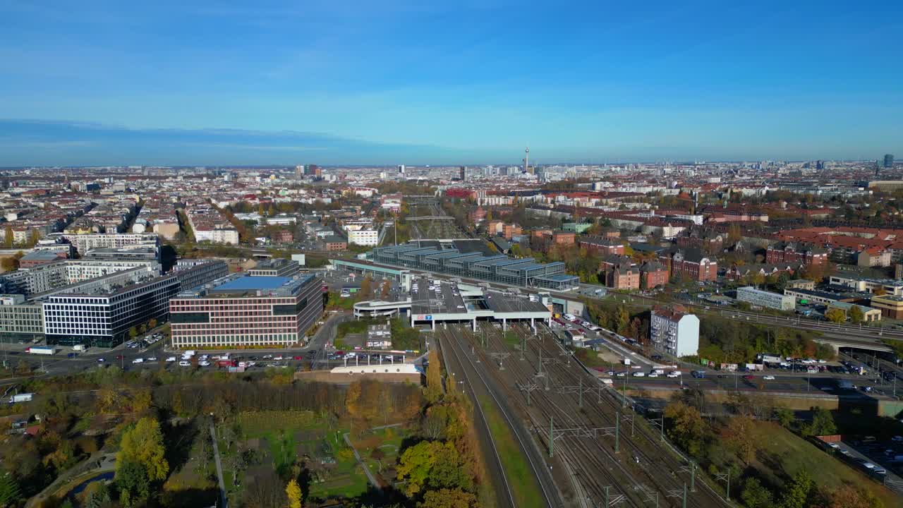 Berlin cityscape with a modern train station South Cross and extensive railway lines under a clear sky. Smooth aerial view flight fly push forward panorama overview drone