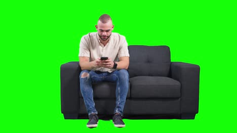 man typing text message on smartphone and laughing, green background