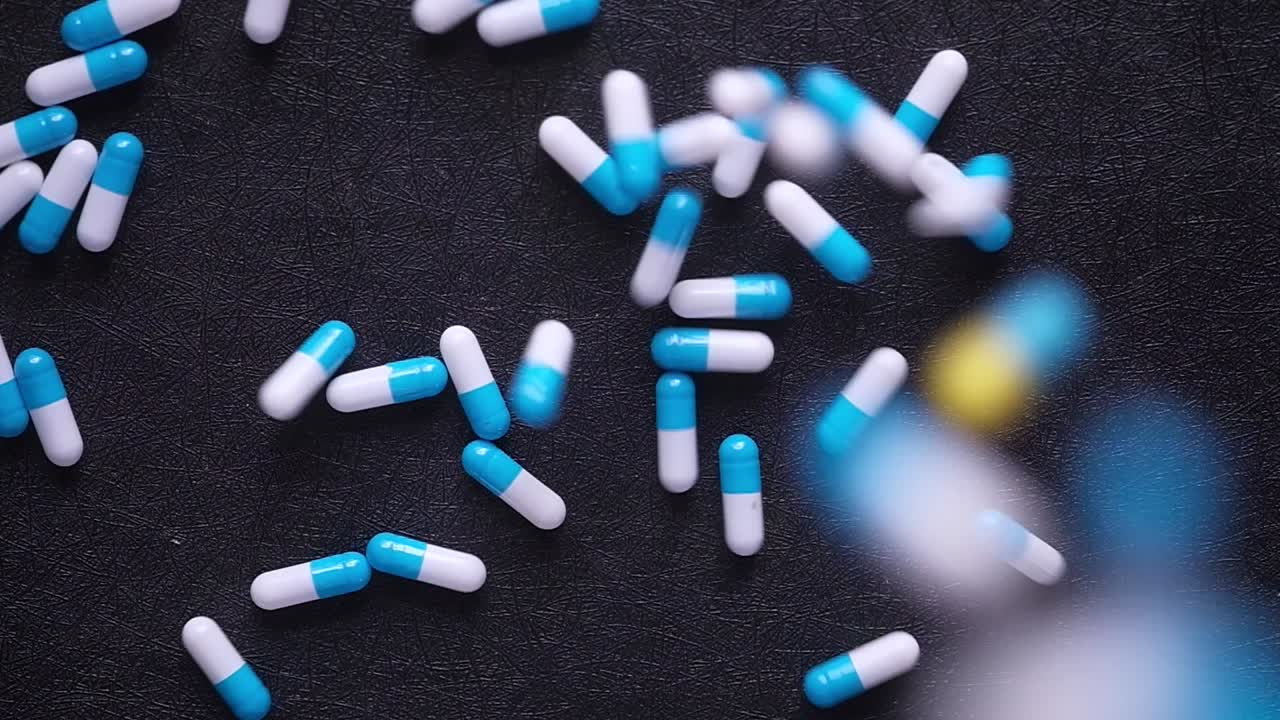 cápsulas azules y blancas esparcidas en una superficie oscura