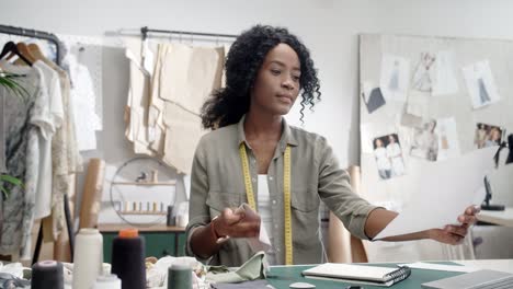 mujer diseñadora de ropa sosteniendo un boceto de un nuevo modelo de colección y poniéndole piezas de ropa y eligiendo qué coincide