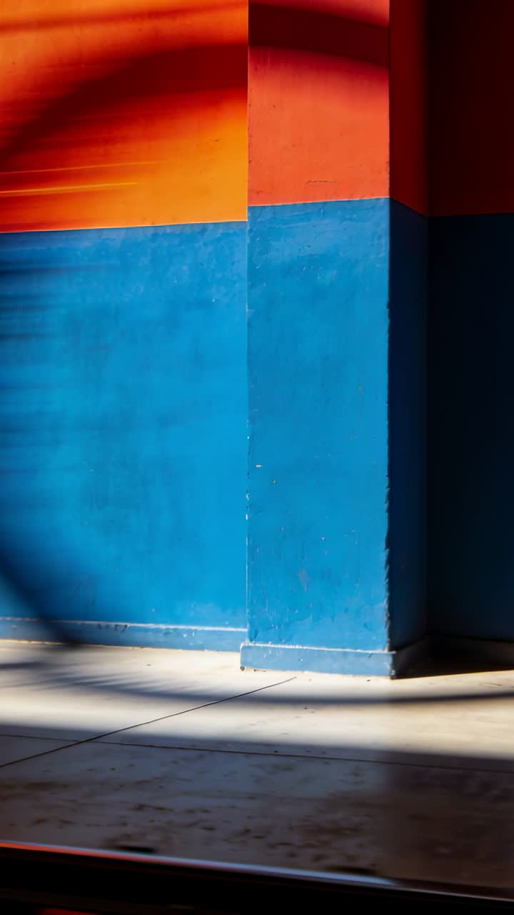 Pared vibrante naranja y azul con luz solar y sombras dinámicas