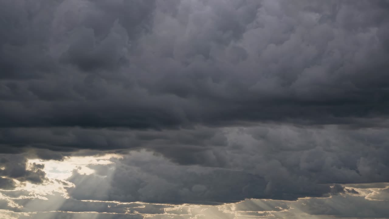 Dramatic video scene of storm clouds with sun rays breaking through, captured from a low angle