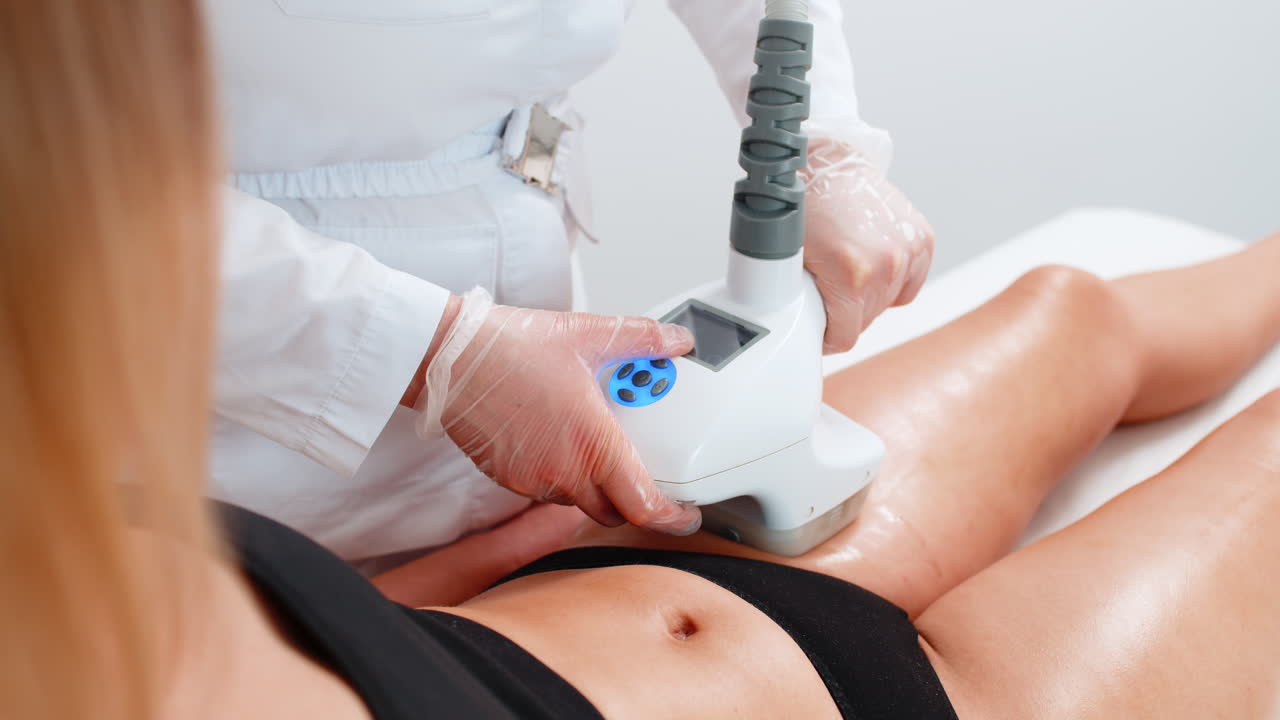 Vrouw krijgt cavitatie vacuümmassage op dijen in schoonheidskliniek door professionele schoonheidsspecialiste