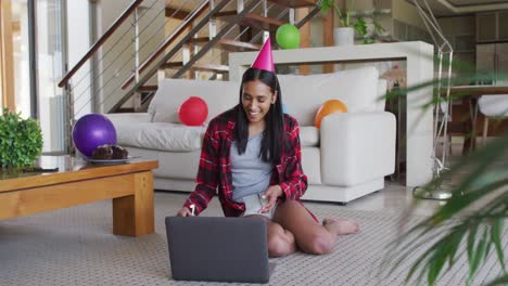 Frau-Mit-Gemischter-Abstammung,-Die-Einen-Laptop-Benutzt-Und-Einen-Videochat-Zum-Geburtstag-Führt,-Der-Einen-Kuchen-In-Der-Hand-Hält