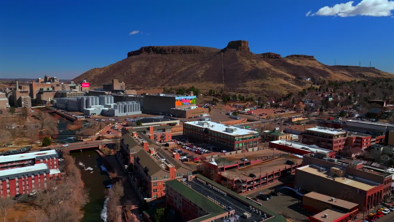 Historic downtown Golden Colorado aerial drone Clear Creek River North Table Mountain Coors Beer Factory Golden Gate Canyon winter sunny morning afternoon blue sky businesses buildings car pan left