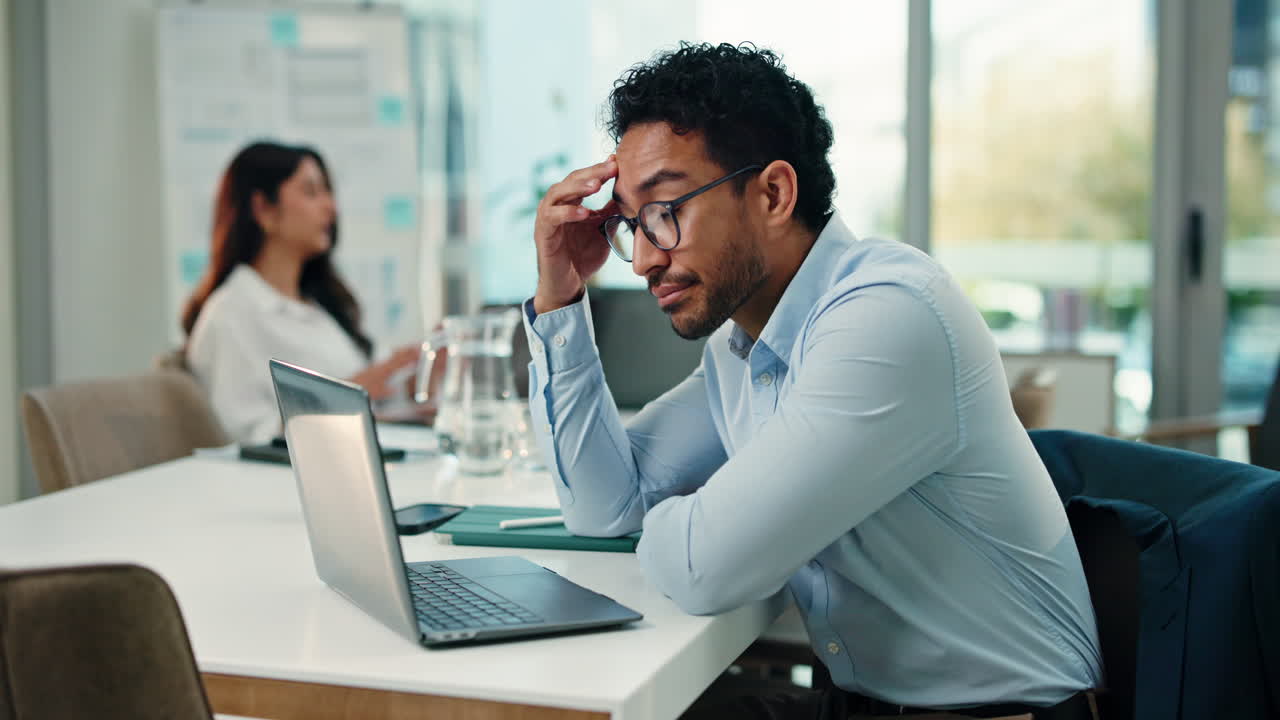 Two business colleagues working in office, one appearing stressed