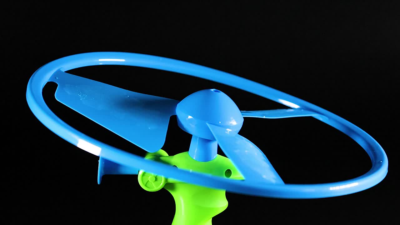 A detailed close-up shot of hands pulling a string to launch a plastic propeller toy