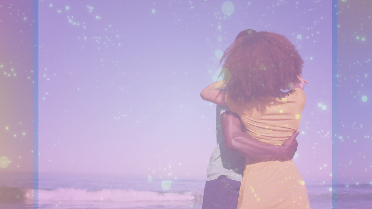 Couple embracing on beach with sparkling light animation over ocean background