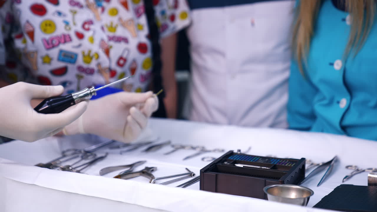 Unrecognized medic teacher in latex gloves shows tools to the group of medics. Dentistry course at medical university.