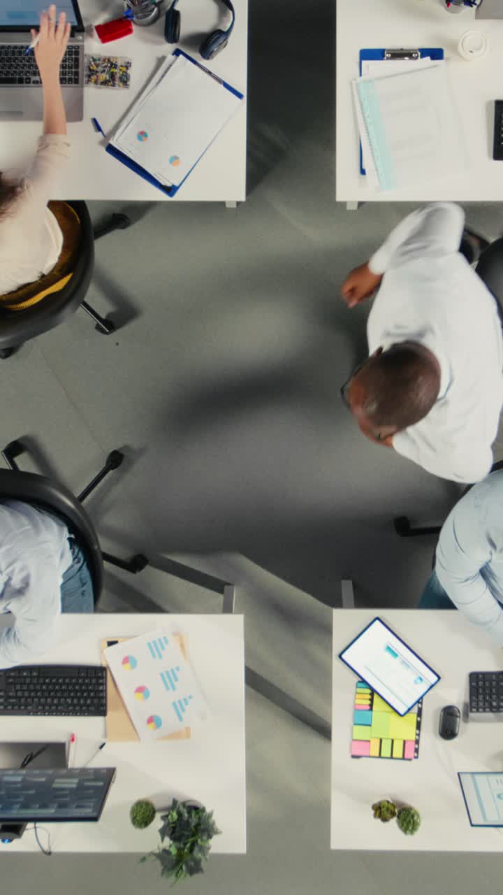 Vertical Video Top down view zoom in of diverse work team study analytics and forecasting