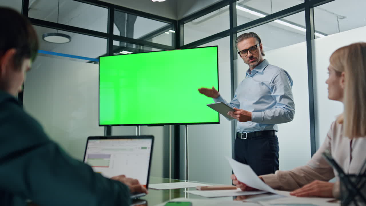 hombre de negocios haciendo chromakey oficina de presentación. entrenador apuntando a la pantalla verde