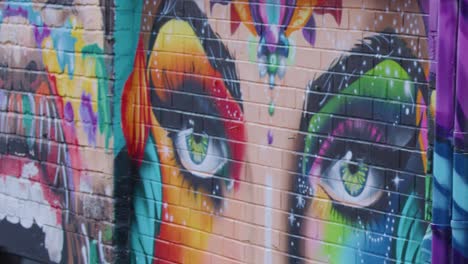 colorful street art mural with rainbow theme, steady daylight pan, urban brick alley location