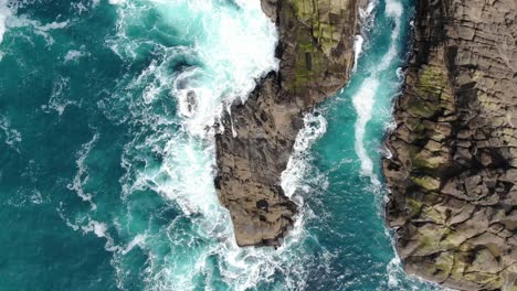 Drone-flies-over-sea-stack-in-beautiful-aqua-water