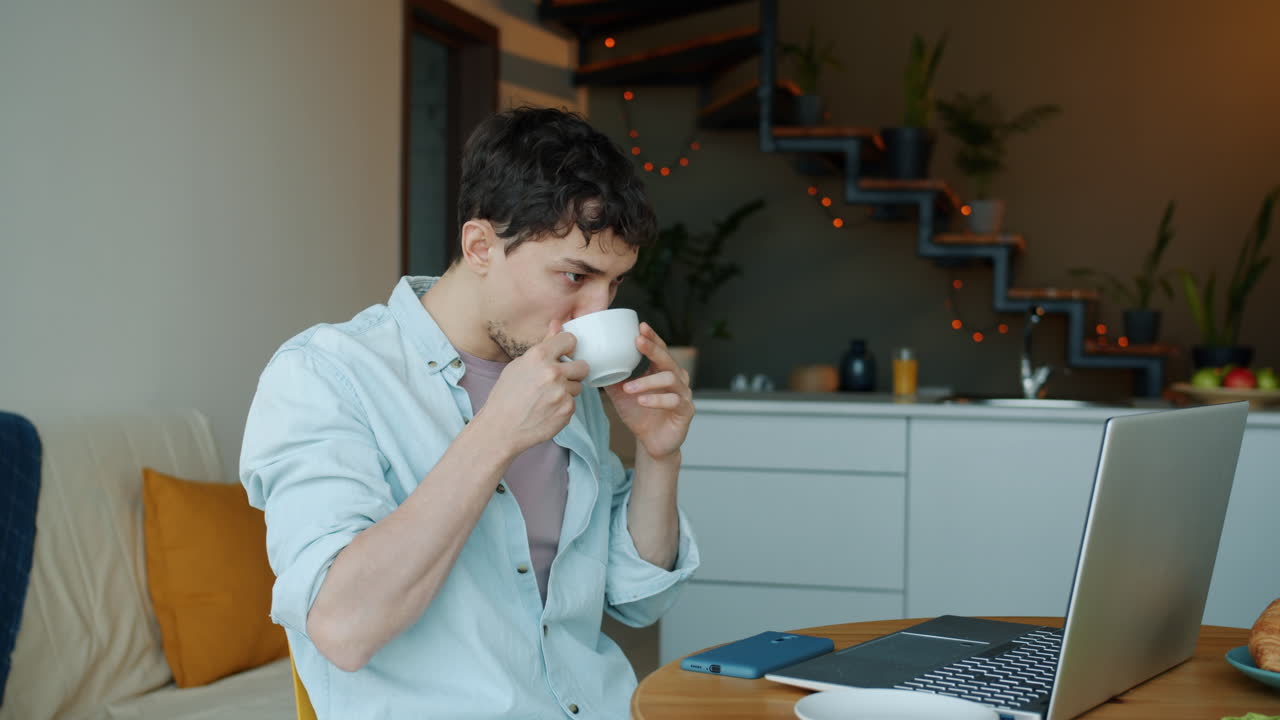 Man working from home, drinking coffee and on a video call