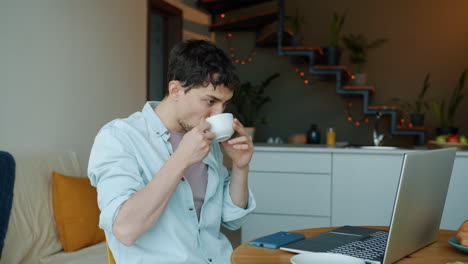 man working from home, drinking coffee and on a video call