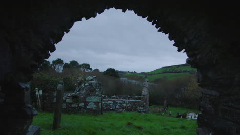 arch ruin of an old stone church with graves ireland