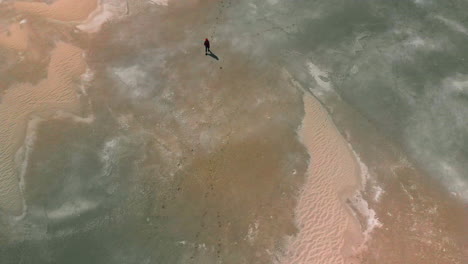 aerial high overhead of a young girl walking on a desolate landscape by the great salt lake