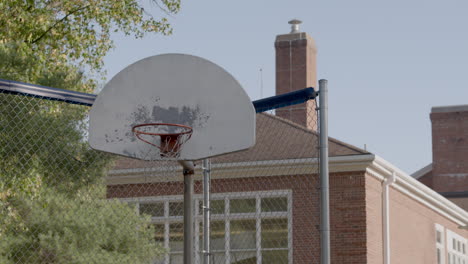 outside basketball net and backboard at a school with track left