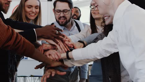 close-up young male boss joining hands with multiethnic team celebrating success at modern office slow motion red epic.