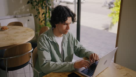 a young man works on his laptop in a cafe.