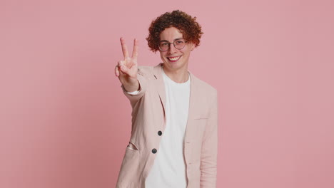 happy smiling young man showing victory sign, hoping for success and win, doing peace gesture