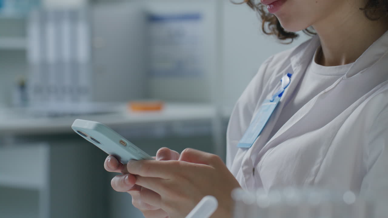 Close-Up of Female Scientist Texting on Phone in Laboratory