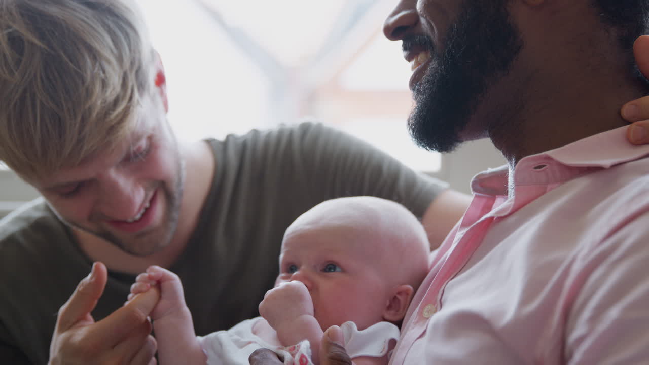 사랑 하는 남성 동성 커플 이 집 에서 함께 소파 에 있는 아기 딸 을  ⁇ 안고 있다